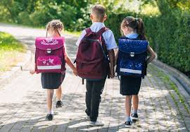 slika djeca sa torbama idu u skolu po popločenom putu u zelenom okolišu